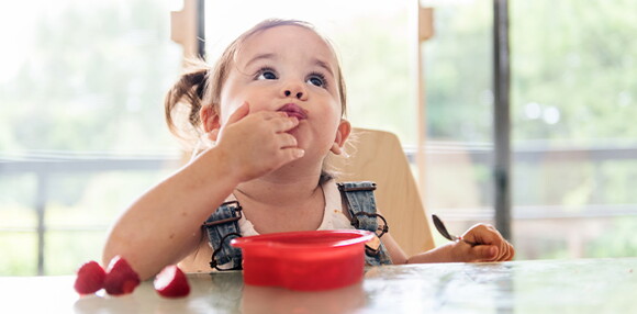 Prueba qué frutas pueden comer los bebés dándole una cada día e identificando sus gustos. Niña comiendo frutilla.