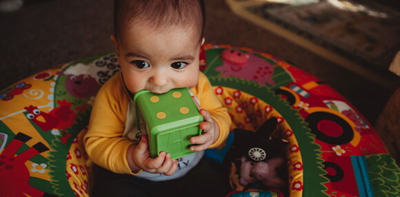 Uno de los tipos de desarrollo psicomotor es el fino donde los niños pueden manipular los juguetes. Niño sentado cogiendo un juguete.