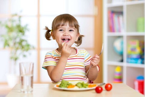 Pequeña comiendo verduras durante la comida.